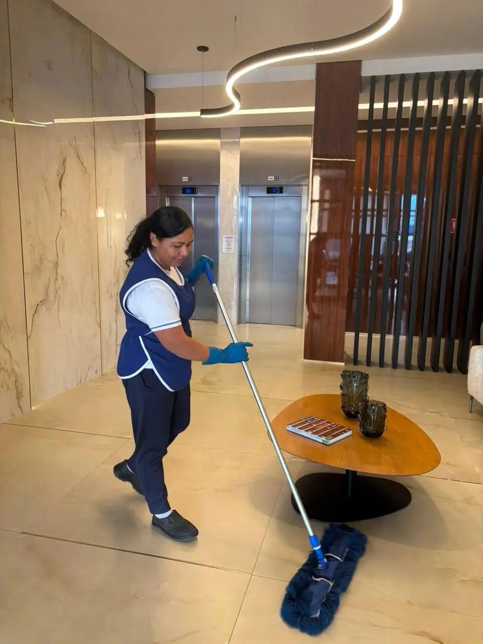 Colaboradora da Mega passando mop no piso do hall de um condomínio